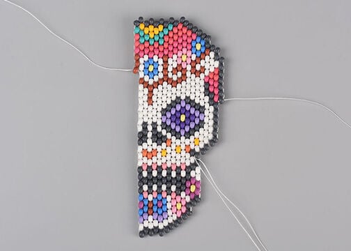 Completed right half of the candy skull with threads coming from the right about 1/3 and 2/3 of the way down the skull. 
